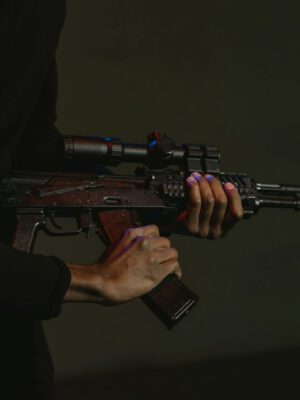 Dramatic image of a person holding a rifle with a scope, taken in low light.